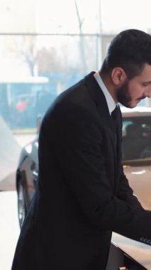 Takım elbiseli bir işadamı modern bir araba galerisinde profesyonellik gösteren belgeler imzalıyor..