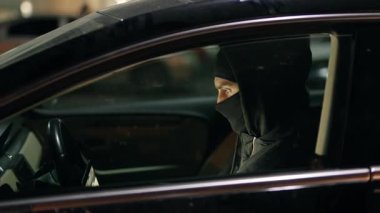 Arabadaki bir kişinin silueti, koyu renk giyinmiş, entrika ve belirsizlik hissi yaratıyor..