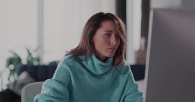 Modern bir çalışma ortamının dinamiklerini örnek alan kararlı bir kadın bilgisayar üzerinde çalışıyor.