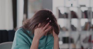 Rahat bir battaniyeye sarılmış düşünceli bir kadın, huzurlu bir iç mekânın derinliklerine yansıyor.