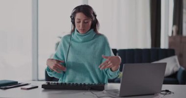 Konforlu bir turkuaz kazak giyen genç bir kadın, dizüstü bilgisayarıyla çok içli dışlı, işine dalmış.