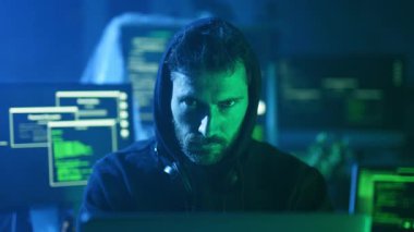 Yaratıcılığı teşvik eden karanlık bir ortamda şifreli ekranlarla çevrili bir dizüstü bilgisayar üzerinde çalışan odaklanmış bir kişi.