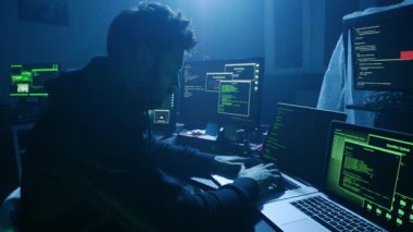 Yetenekli bir siber güvenlik uzmanı odaklanmak için karanlık bir ortamda birden fazla ekrandaki hassas verileri analiz eder.