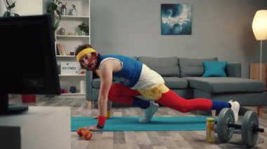 Spor meraklısı evde renkli kıyafetler giyer ve elinde dambıllarla spor yapar.