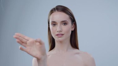 Cesur ve kendinden emin genç bir kadın minimalist bir ortamda duruyor, büyük bir titizlikle ve özgüvenle hareket ediyor.