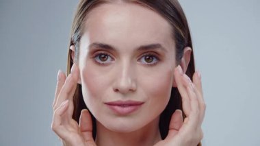 Nazik el hareketleri ve jestleri kullanarak çeşitli cilt tekniklerini ustalıkla sergileyen sakin ve zarif bir kadın.