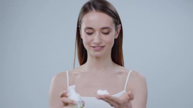 Huzurlu genç bir kadın lüks bir cilt bakımı ürünü uyguluyor, güzelliği, sağlığı ve kişisel bakım ritüellerini destekliyor.