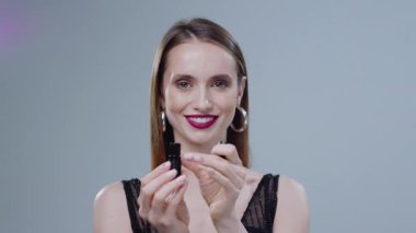 Kendine güvenen ve dengeli bir kadın modern ortamda göz alıcı ve şık bir kozmetik ürün sergiliyor.