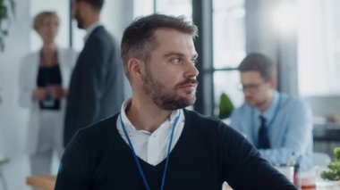 Modern bir ofiste sakallı bir adam iş arkadaşlarıyla işbirliği yapar, görüşlerini paylaşır ve etkili bir iletişim yoluyla olumlu, etkileşimli bir atmosferi teşvik eder.