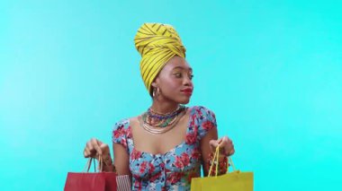 Neşeli bir kadın rengarenk alışveriş çantalarını göz alıcı parlak bir zemin üzerinde gururla sergiliyor