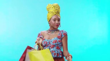 Renkli alışveriş torbalarıyla poz veren şık bir kadın, canlı moda ve modaya uygun aksesuarlar sergiliyor.