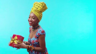 Neşeli ve neşeli bir kadın rengarenk kıyafetleriyle kutlama yaparken güzel bir hediye tutuyor.