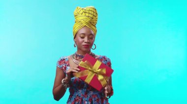 Kırmızı bir hediye kutusu tutan şık bir kadın. Renkli geleneksel kıyafetlerle donatılmış..