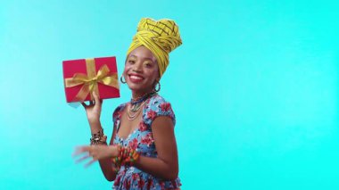 Şık bir kadın güzel bir hediyeyle poz verir, canlı kıyafetlerini şenlikli bir atmosferde sergiler.