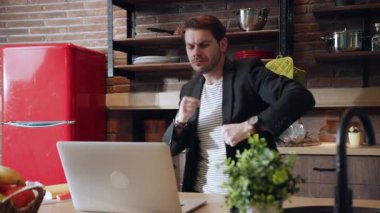 Genç ve hevesli bir profesyonel modern bir mutfakta dizüstü bilgisayarlarında üretken işler yapıyor.