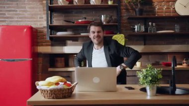 Neşeli ve hevesli bir birey şık bir mutfak masasında rahatça otururken alkışlıyor.