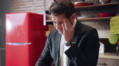 Takım elbiseli çalışkan bir adam modern bir ev ofisinde çarpıcı bir kırmızı buzdolabı ile etkili bir şekilde çalışır.