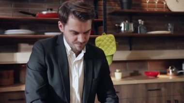 İyi giyimli bir adam şık, çağdaş bir mutfak ortamında yemek hazırlama sanatıyla ustaca ilgilenir.