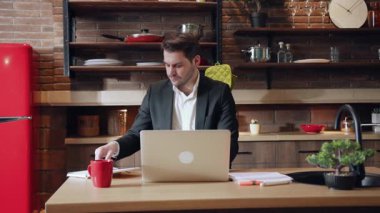 Odaklanmış ve kararlı bir genç adam, şık ve çağdaş bir ofis ortamında özenle dizüstü bilgisayarı üzerinde çalışıyor.