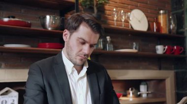 Şık bir mutfakta çalışan odaklanmış bir işadamı profesyonellik ve homelliğin bir karışımını sergiliyor..