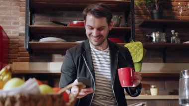 Bir adam kahvesinin tadını çıkarıyor şık, modern bir mutfakta, yanında bir dizi taze meyve var.