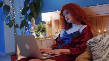 Sakin ve sakin bir iç mekan sahnesi, bir insanın dizüstü bilgisayarını rahat ve hafif aydınlatılmış bir ortamda kullandığını gösteriyor.