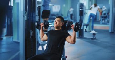 Dambıllı yakışıklı genç sporcu eğitimi. Asyalı sporcu vücut geliştirici profesyonel spor salonunda güç için çalışıyor..