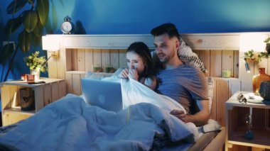 Bir ebeveyn ve çocuğun yataklarında keyifli bir film gecesini canlandırdıkları sıcak ve samimi bir an.