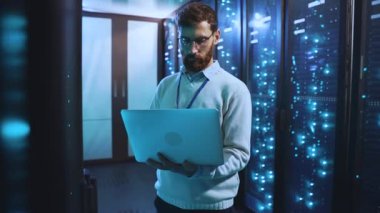 Bir teknisyen sunucu odasında çalışır, sistemleri izlemek ve bakımını yapmak için dizüstü bilgisayar kullanır, modern teknoloji ve uzmanlığı sergiler.