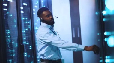 Bu videoda, bir adam yüksek teknoloji sunucu odasını keşfediyor, dizüstü bilgisayarındaki görevleri yönetiyor ve IT 'de bir walkietalkie kullanarak, takım çalışmasını gösteriyor.