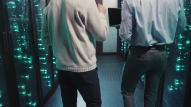 İki kişi bir veri merkezinde teknoloji ve altyapıyı tartışarak sunucu ve ağ donanımlarıyla dolu yüksek teknolojili bir sunucu odasını keşfediyor.