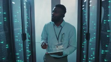 Bu videoda, bir teknoloji uzmanı sunucu odasını keşfetmek için bir tablet kullanıyor, veri merkezlerinin nasıl çalıştığını ve bağlanabilirliğin önemini gösteriyor.