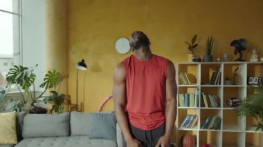 Bu eğlenceli videoda, bir adam oturma odasını hayat dolu bir yaşam alanına çeviriyor. Yoga minderi kuruyor ve hula hoop kullanıyor, rahatlamayla enerji egzersizlerini harmanlıyor.