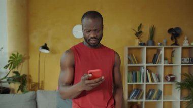Sıcak bir oturma odasında, bir adam akıllı telefonunu kullanır, başlangıçta dalgındır. Etkileştikçe, bir gülümseme yayılıyor, iyi haberler ve sevinç telkin ediyor.