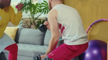 Canlı bir oturma odasında, iki arkadaş birlikte çalışırlar. Biri bir dambılı kaldırırken diğeri onu cesaretlendirir. Kanepede şınav çekip fitness ve dostluk gösteriyorlar.
