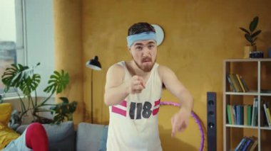 Bu eğlenceli videoda, bir adam beyaz atlet ve saç bandıyla hulahop yeteneklerini sergiliyor, izleyicileri eğlendirirken enerji ve mizah yayıyor.