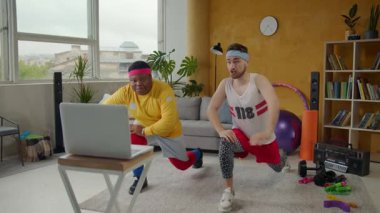 Canlı bir oturma odasında iki adam ve bir çift bir dizüstü bilgisayarda online ders yapıyorlar. Enerji ve kararlılık sergiliyorlar.