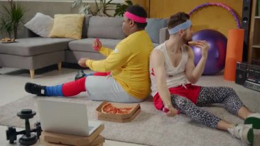 Sıcak bir oturma odasında, iki arkadaş gülüyor ve bir film gecesi için yerde pizza paylaşıyorlar, bu arada bir çift arka arkaya bağlanıyor, rahatlığın tadını çıkarıyorlar.