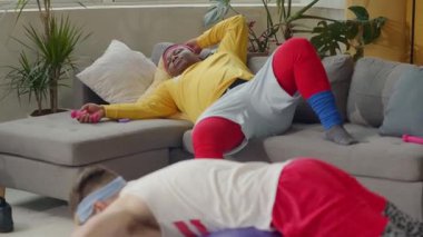 Samimi bir sahne, diğerleri çalışırken bir adamın kanepede dinlendiğini gösteriyor. Bir kadın pilates topu kullanır, güç ve dengeyi harmanlar.