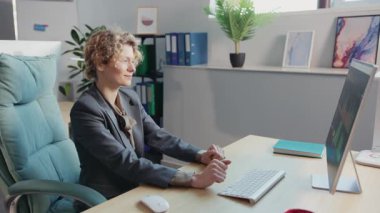 İşbirlikçi bir çalışma alanında masasında yazı yazan bir kadın, bir erkek bilgisayarla uğraşırken, takım çalışmasını ve üretkenliğini ön plana çıkarırken,