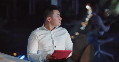 Odaklanmış bir adam, gece geç saatlere kadar şık ve modern bir ofiste otururken yenilikçi fikirleri derinden düşünür.