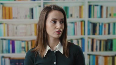 Yoğun bir kütüphanede, genç bir kadın bilgilerini ve bağlılığını kaynak ortamında sergiliyor.