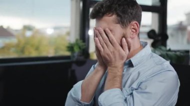 Bakımlı sakallı bir adam şık bir ofiste oturuyor, düşüncelere dalmış ve düşüncelere dalmış.