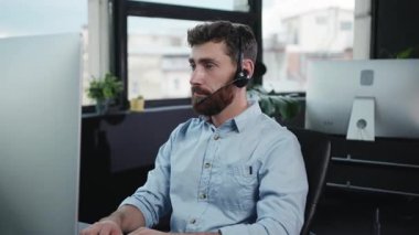 Kendini işine adamış bir erkek müşteri hizmetleri temsilcisi masasında modern ekipmanlarla bir telefon görüşmesi yaptı..