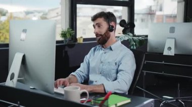Kendini işine adamış bir adam modern ve çağdaş ofis ortamında yüksek teknolojili bir bilgisayarda çalışıyor.