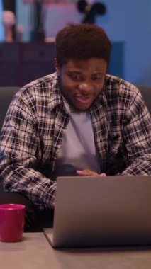 Şık bir dekorun bulunduğu rahat bir yaşam alanında genç bir adam dizüstü bilgisayarıyla çok meşgul ve odaklanmış durumda.