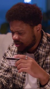 Rahat bir ortamda, genç bir adam telefonuna odaklanmış, konsantrasyon ve duyguların karışımını gösteriyor.