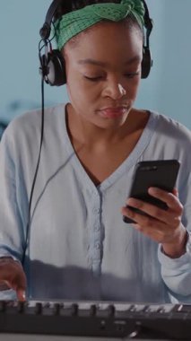 Bu videoda, bir kadın telefonuyla iletişim kurarken klavye çalıyor. Odağı teknoloji ve sanatın karışımını yansıtıyor.