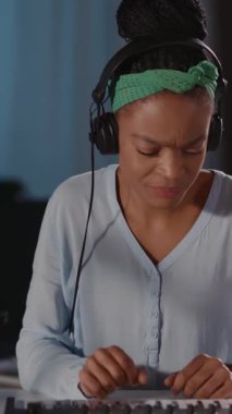 Kulaklıklı ve yeşil bantlı bir kadın yaratıcı bir müzikal yolculuktan zevk alıyor, odaklanarak klavye çalıyor, ifadelerini ve müzikle bağlantısını yakalıyor.