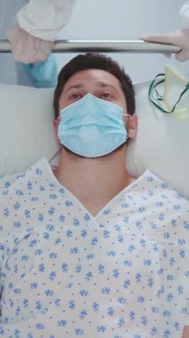 Hastalıklı, hasta, sakallı bir adam sedye yatağında yatıyor ve acil servise naklediliyor. Covid-19 salgını. Coronavirus. Salgın, hastalar ve klinik konsepti.